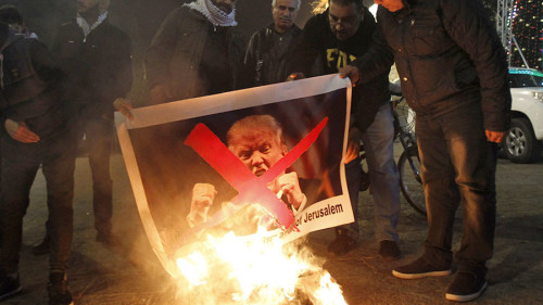 I manifestanti palestinesi bruciano le immagini del presidente degli Stati Uniti Donald Trump nella piazza della mangiatoia a Betlemme il 5 dicembre 2017